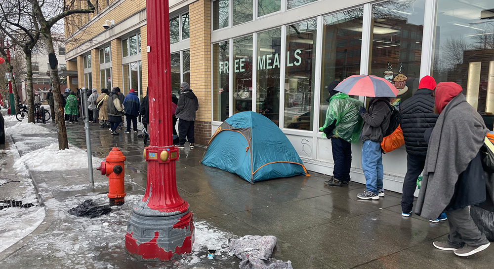 Line of people wait for meals which reflects the increase in homelessness reported in the 2023 Point in Time count
