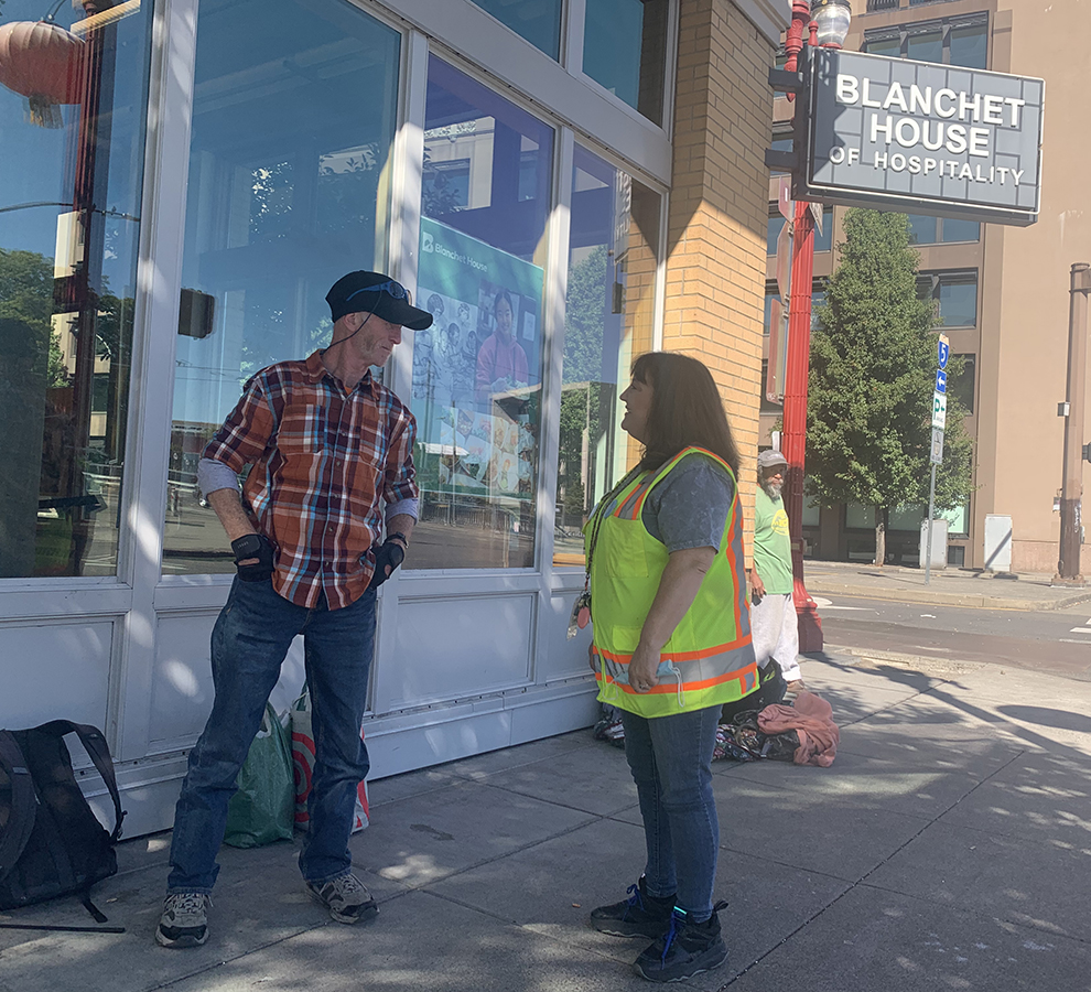 Peer Support Specialist Jennifer Coon talks to homeless man outside Blanchet House