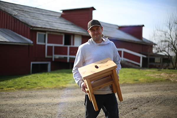 Lucas shows a cedar stool he made at Blanchet Farm in Carlton, Oregon