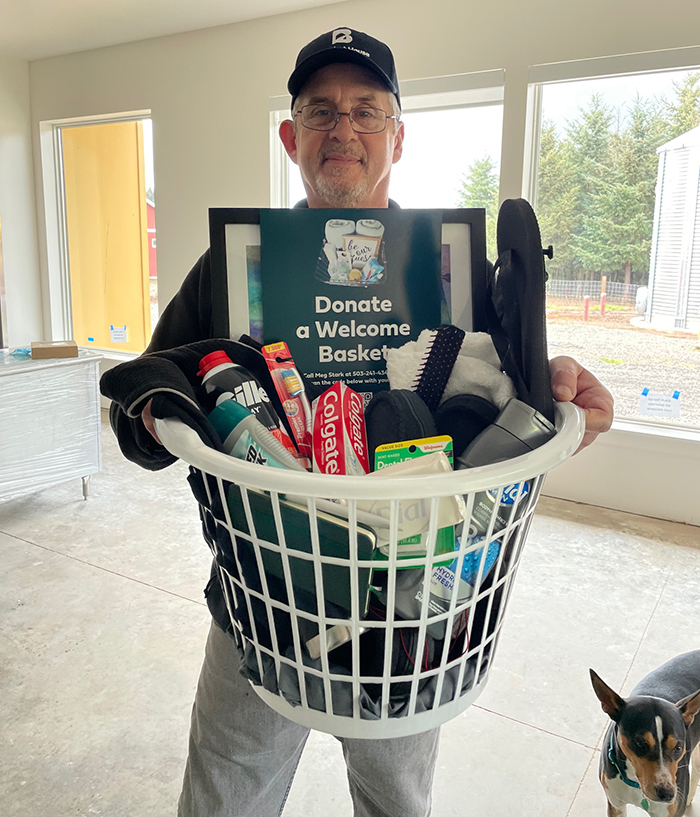 Ross Sears holds welcome basket for a farm resident in the final push to finish the farm construction.
