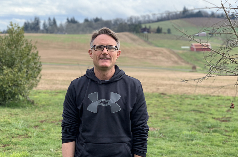 Man standing in field at addiction recovery farm