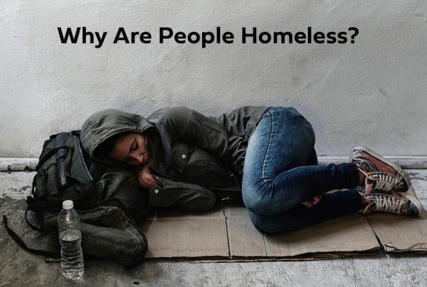 Why are people homeless? A woman lies on the ground.