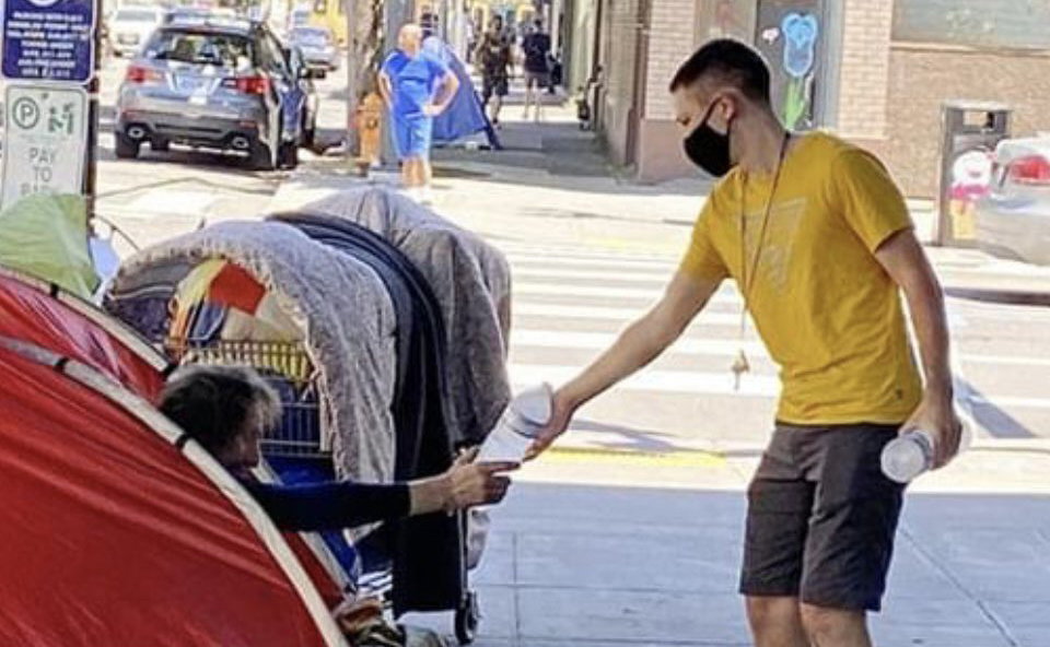 A volunteer offers a homeless man water in Portland to prevent dehydration during a summer heat wave.